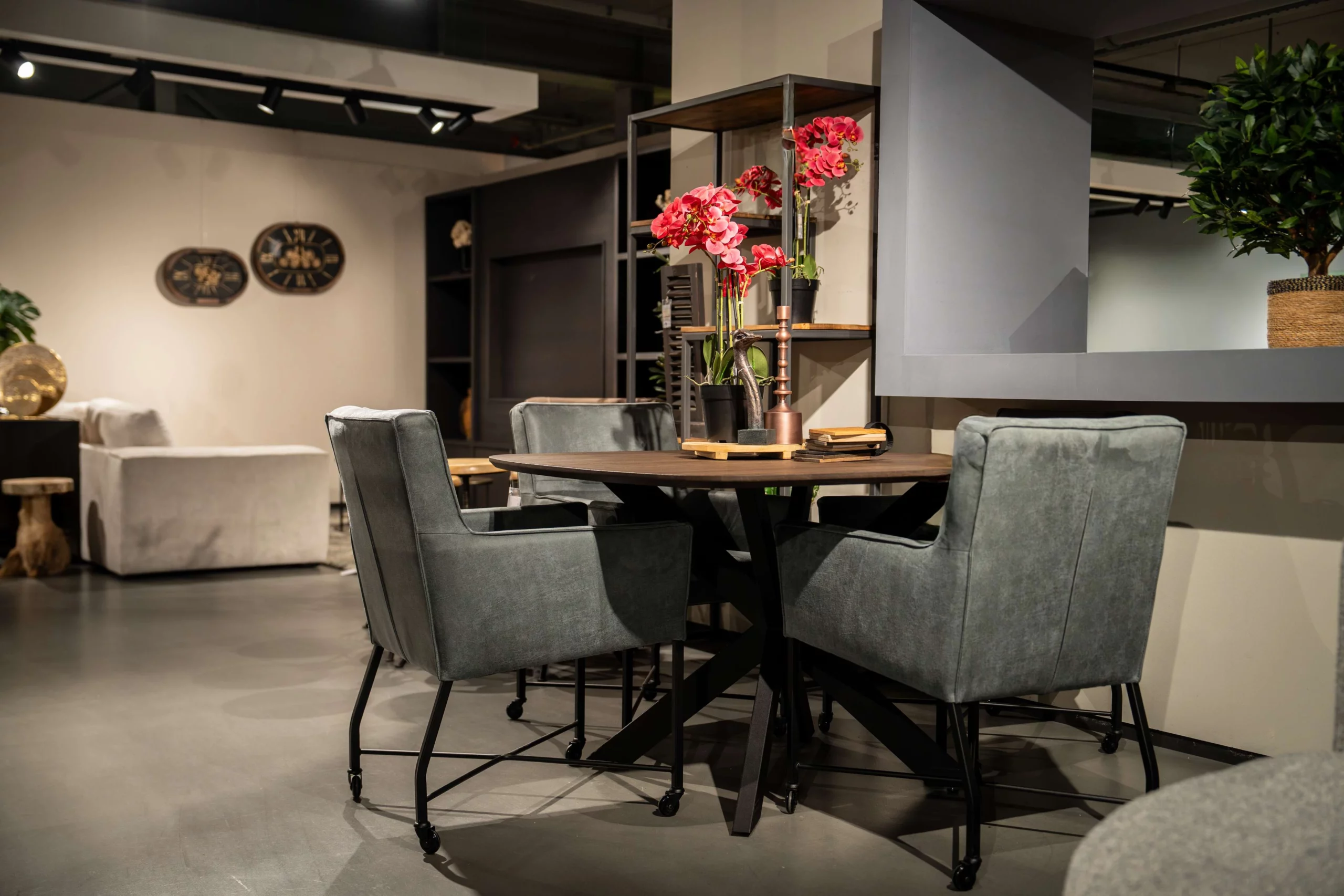 Ronde houten eettafel met zwarte metalen kruispoot en donkerblauwe eetkamerstoelen