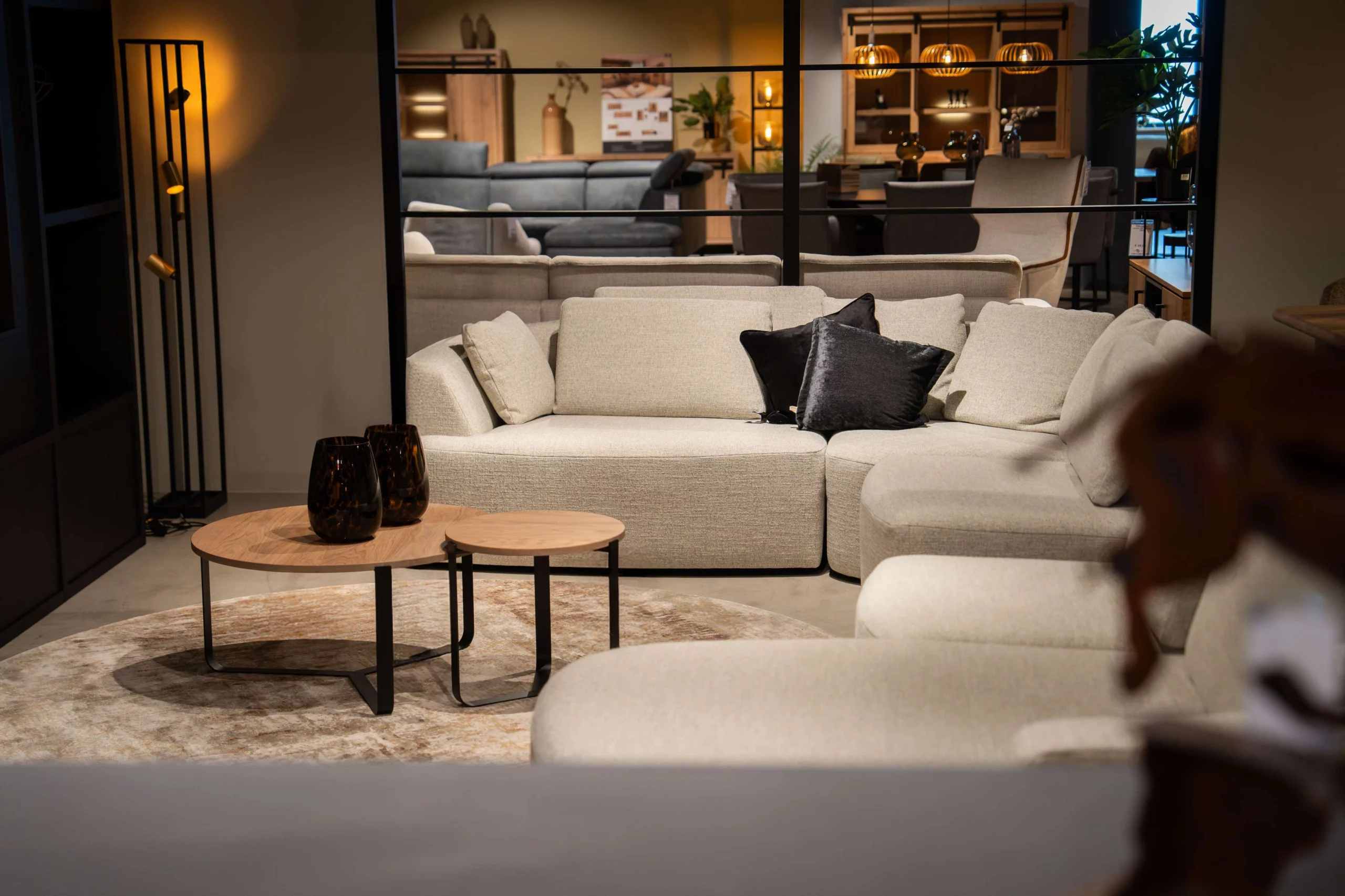 Kleine houten salontafeltjes voor een witte stoffen bank met donkere sierkussens