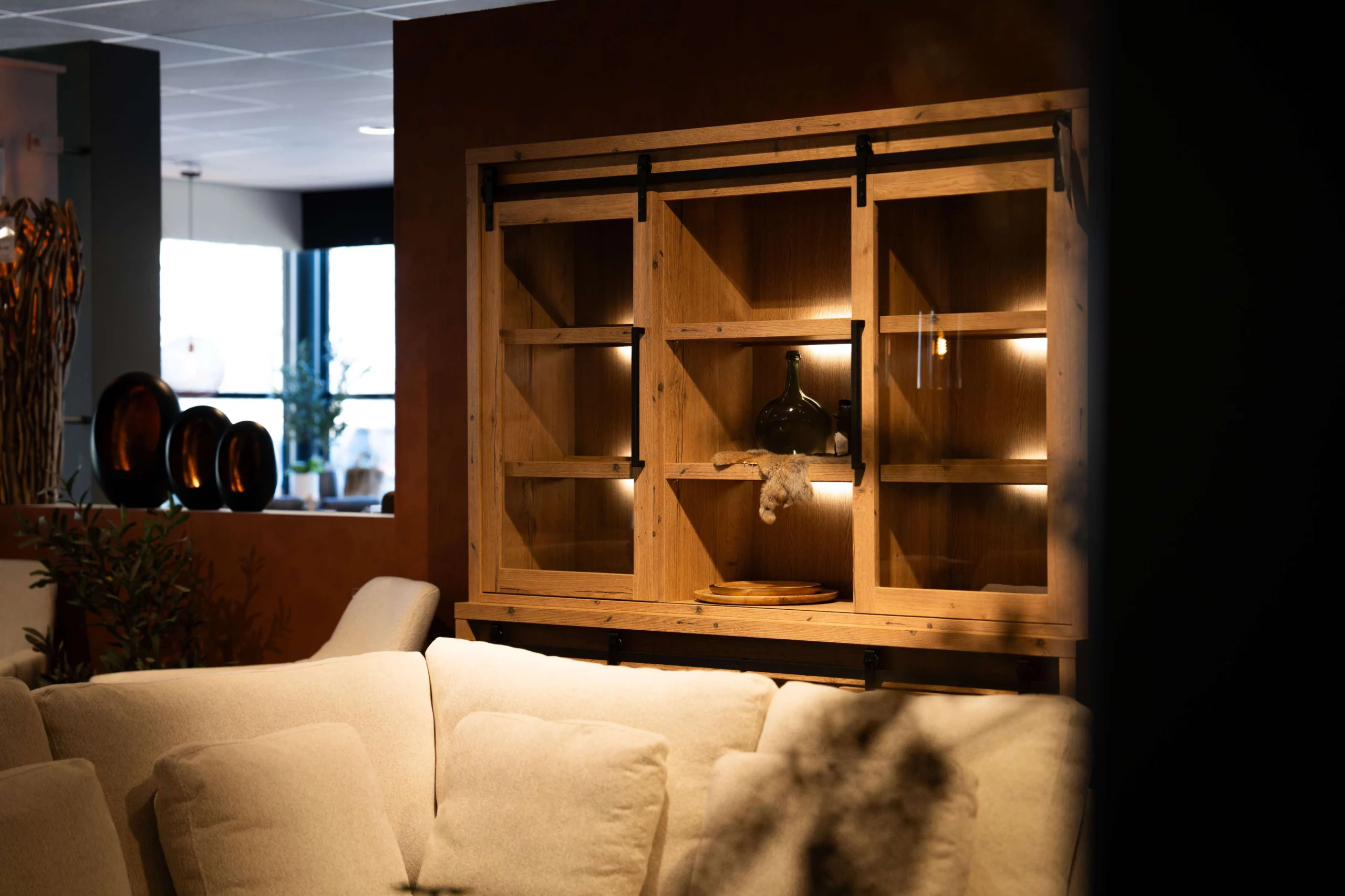 Grote houten vitrinekast met lampjes en woonaccessoires