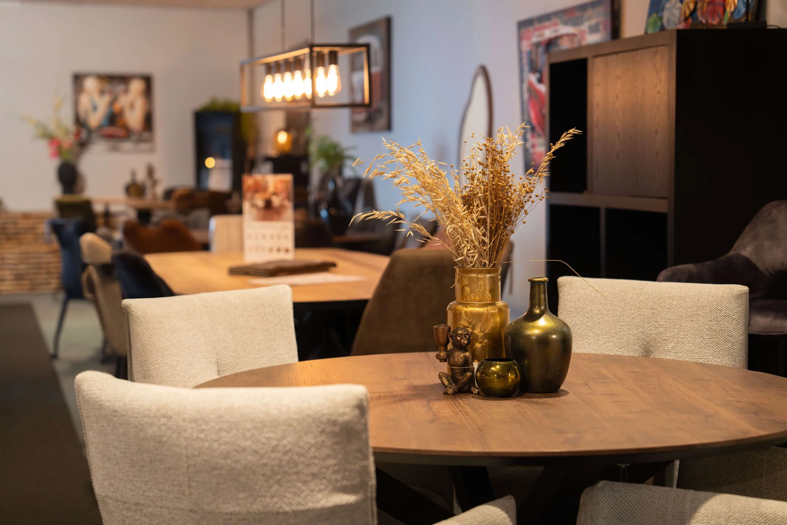 Woonaccessoires op een ronde eettafel omringd door lichte eetkamerstoelen
