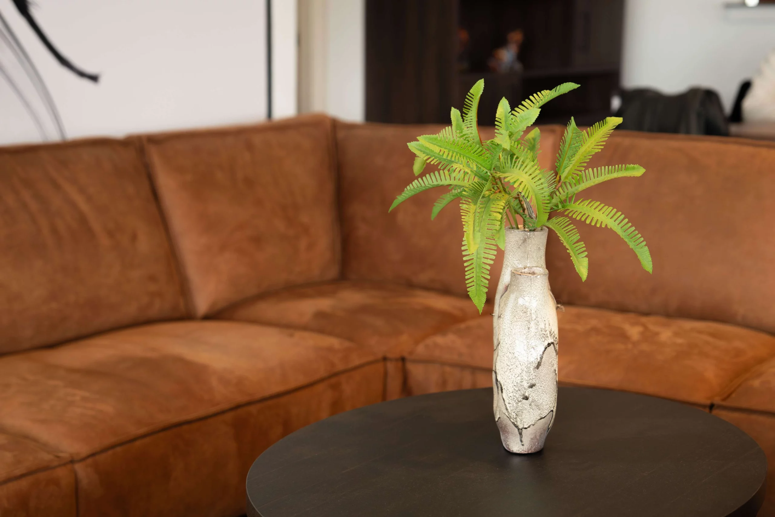 Klassieke cognac hoekbank met een vaas op de salontafel ervoor